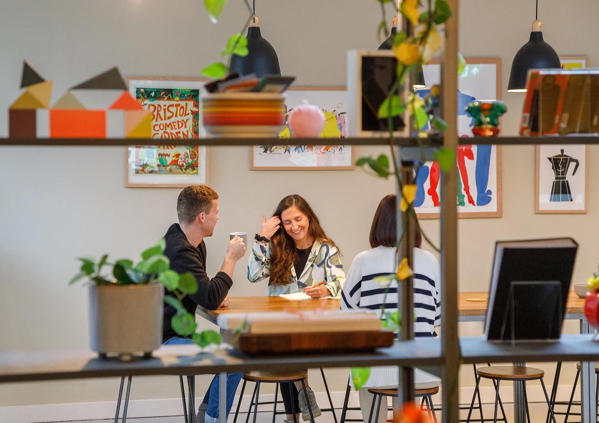 Casual meeting of three coworkers at a table.